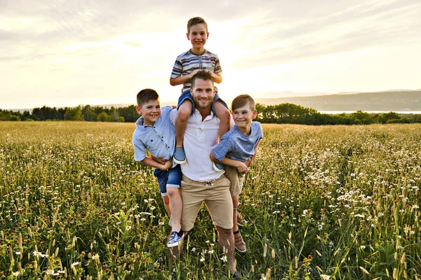 Mutlu bir baba ve iki çocuk gün batımında sahada eğleniyorlar. — Stok fotoğraf