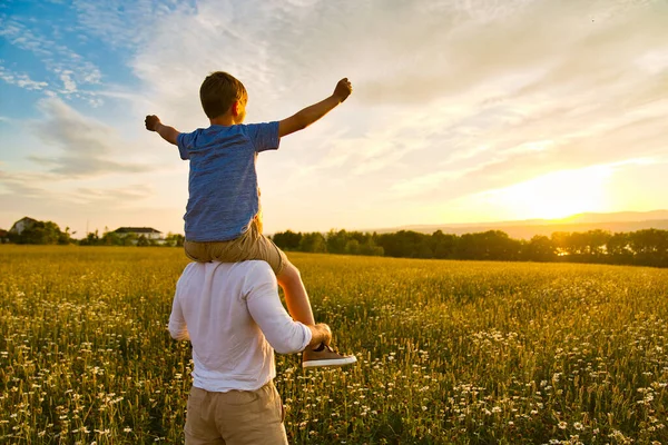 Felice famiglia di padre e figlio sul campo al tramonto divertendosi — Foto Stock