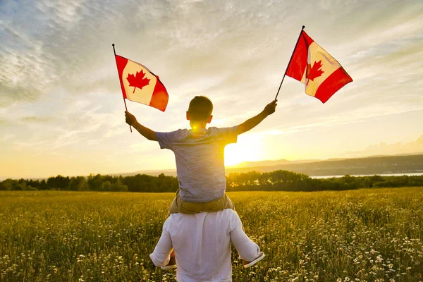 Симпатичный счастливый белый мальчик с канадским флагом на плече отца. — стоковое фото