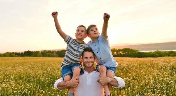 Gelukkig gezin van vader en twee kinderen op het veld bij zonsondergang plezier hebben, sterke broer — Stockfoto