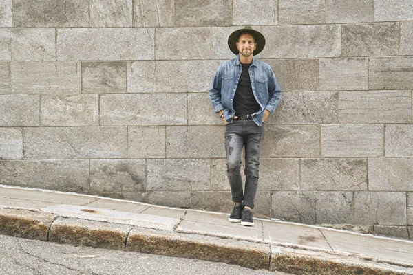 Случайный молодой человек стоит у бетонной стены — стоковое фото
