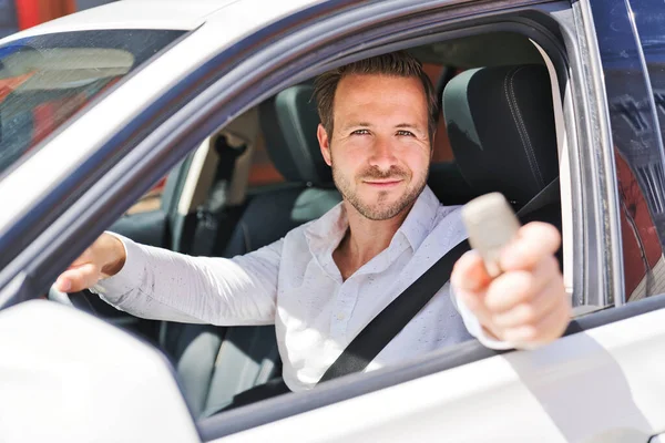 Een portret van een man op zijn auto ziet er leuk uit met zijn sleutel in zijn hand — Stockfoto