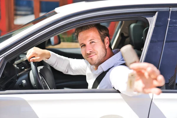 Een portret van een man op zijn auto ziet er leuk uit met zijn sleutel in zijn hand — Stockfoto