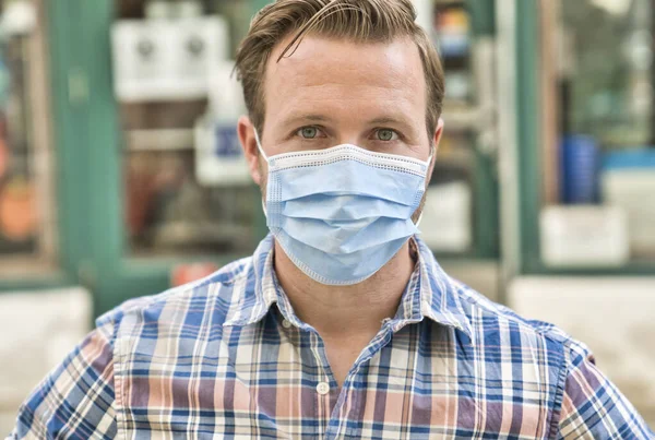 Portrait of brunette man in a medical surgical mask in the summer city. Coronavirus, illness, infection, quarantine. — Stock Photo, Image