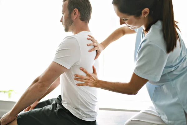 Fisioterapeuta haciendo tratamiento con paciente en consultorio luminoso — Foto de Stock