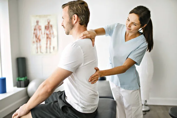 Physiotherapeut behandelt Patientin im hellen Büro — Stockfoto