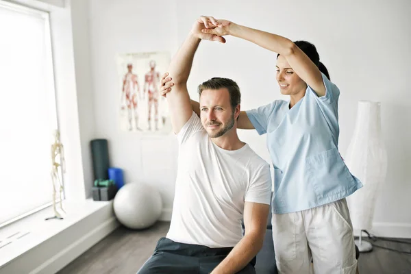 Physiothérapeute faisant un traitement avec le patient dans un bureau lumineux — Photo