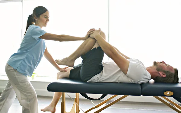 Fysiotherapeut doet behandeling met patiënt in helder kantoor met beentraining — Stockfoto