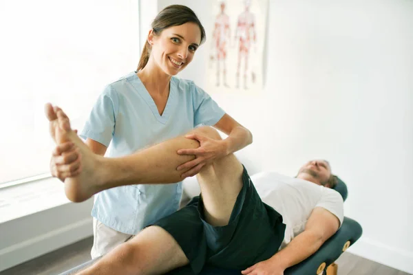 Φυσιοθεραπευτής που κάνει θεραπεία με ασθενή σε φωτεινό γραφείο με εκπαίδευση ποδιών — Φωτογραφία Αρχείου