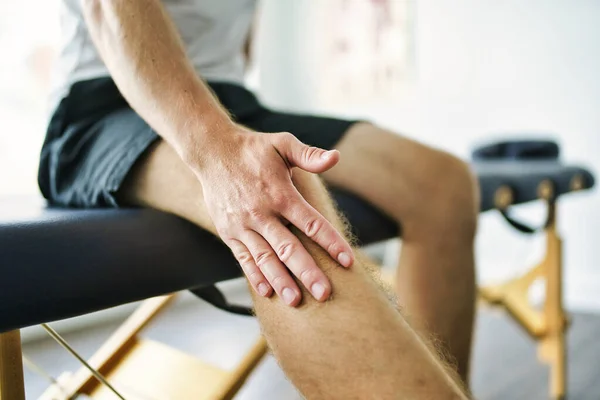 En modern rehabilitering sjukgymnastik plats med man klient sitta på bordet — Stockfoto