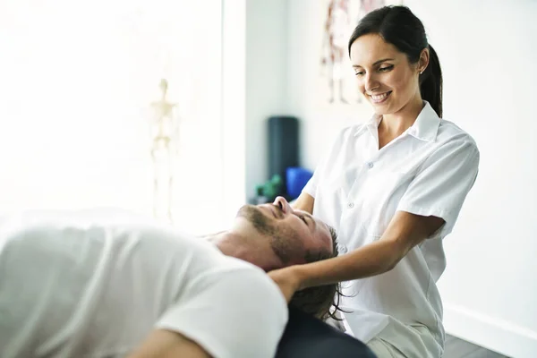 Fisioterapeuta haciendo el tratamiento del cuello con el paciente en la oficina brillante — Foto de Stock