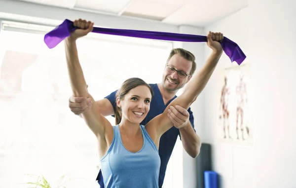 Fisioterapeuta masculino Estirando a una paciente femenina lentamente. — Foto de Stock