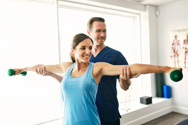 Mannelijke fysiotherapeut die langzaam een vrouwelijke patiënt uitrekt. — Stockfoto