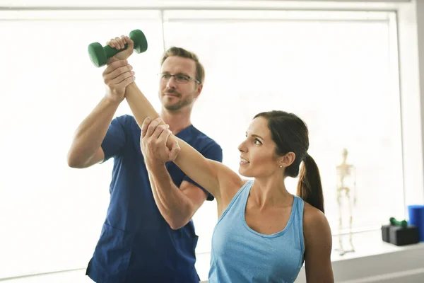 Fisioterapeuta masculino Estirando a una paciente femenina lentamente. — Foto de Stock