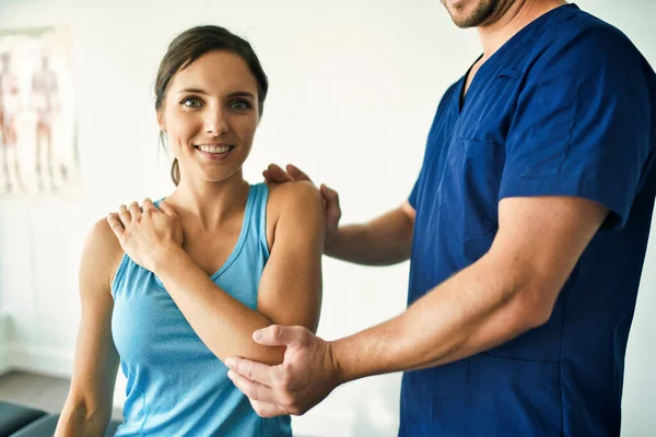 Fisioterapeuta masculino Estirando a una paciente femenina lentamente. — Foto de Stock