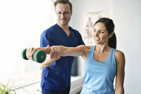 Fisioterapeuta masculino Estirando a una paciente femenina lentamente. — Foto de Stock