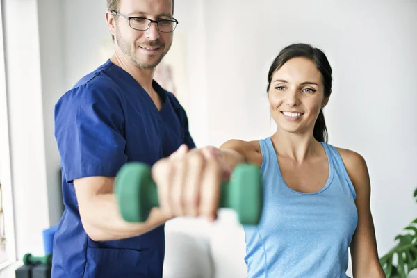 Fisioterapeuta masculino Estirando a una paciente femenina lentamente. — Foto de Stock