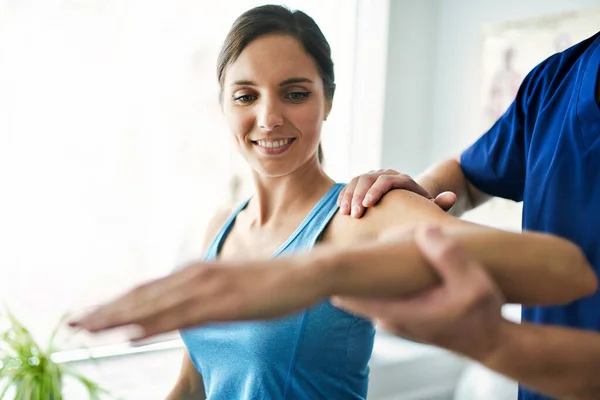 Fisioterapeuta masculino Estirando a una paciente femenina lentamente. — Foto de Stock