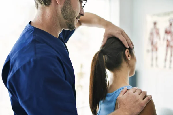 Männlicher Physiotherapeut streckt eine weibliche Patientin nack — Stockfoto