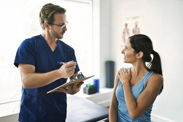 Fisioterapeuta masculino Estirando a una paciente femenina lentamente. — Foto de Stock