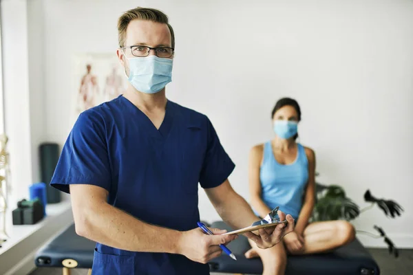 Mannelijke fysiotherapeut met vrouwelijke patiënt op de rug — Stockfoto