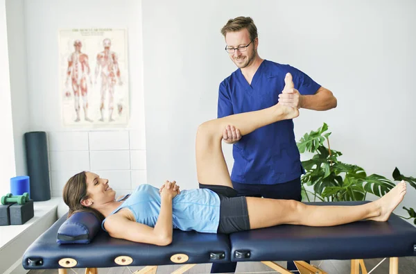 Fisioterapeuta masculino Estirando a una paciente femenina — Foto de Stock