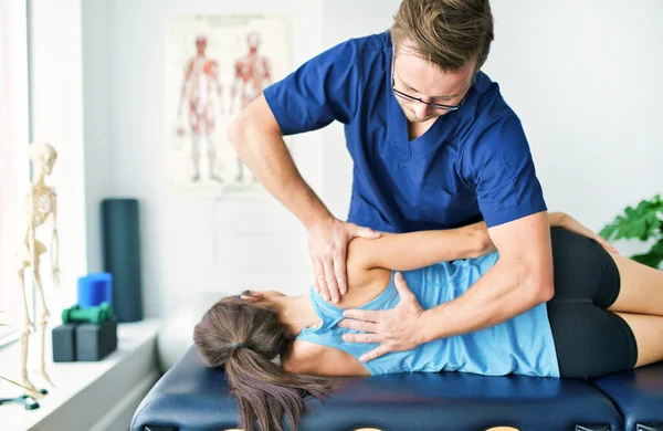 Mužský fyzioterapeut roztahuje pacientku — Stock fotografie