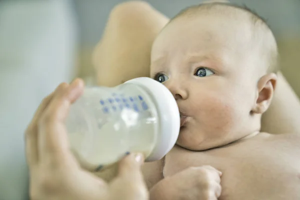 Крупним планом мати годує дитину пляшкою молока вдома — стокове фото