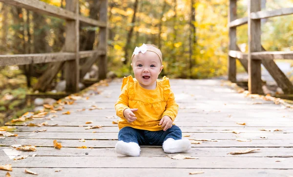 Ребенок сидит на мостике с опавшими листьями — стоковое фото