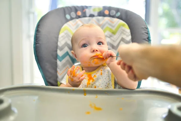 Una pequeña y linda hija feliz con comida de puré por todas partes — Foto de Stock