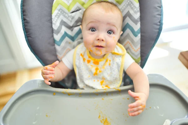 Una niña linda y feliz con comida de puré por todas partes — Foto de Stock