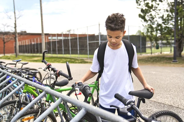 Garçon à vélo portant un casque à l'extérieur de l'aire de jeux de l'école — Photo