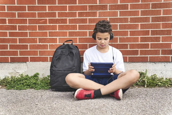 Nastolatek chłopiec słuchanie i grać tablet w szkole plac zabaw — Zdjęcie stockowe