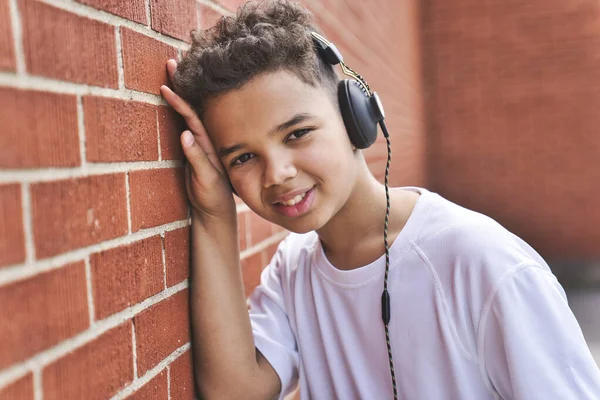 Trevlig afro amerikansk tonåring pojke lyssna musik på skolgården tegelvägg — Stockfoto