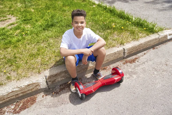 Beau portrait d'un garçon noir exécutant un mini scooter électrique — Photo