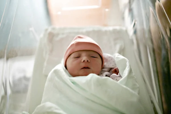 Yeni doğmuş bebek uyuyor, hastane battaniyesine sarılmış ve şapka takıyor. — Stok fotoğraf