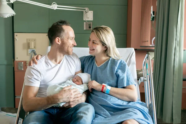 Mother and father with her newborn baby at the hospital a day after a natural birth labor
