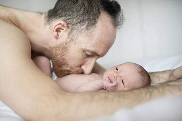 Un padre con un neonato a letto — Foto Stock