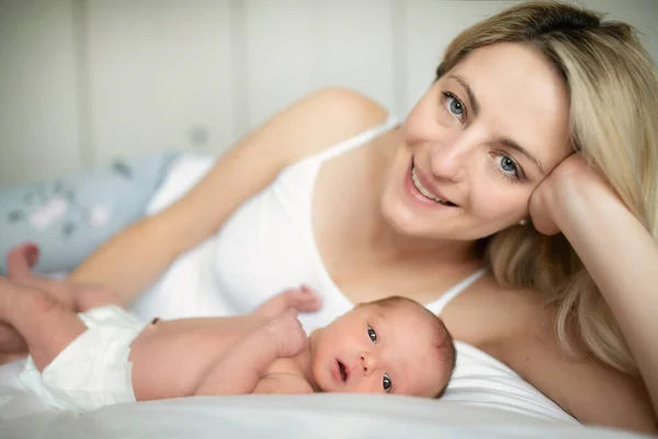 Una mujer con un bebé recién nacido en la cama — Foto de Stock
