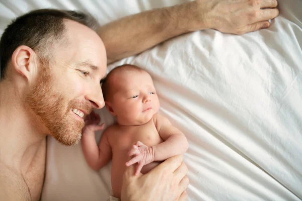 Um pai com um bebê recém-nascido na cama — Fotografia de Stock