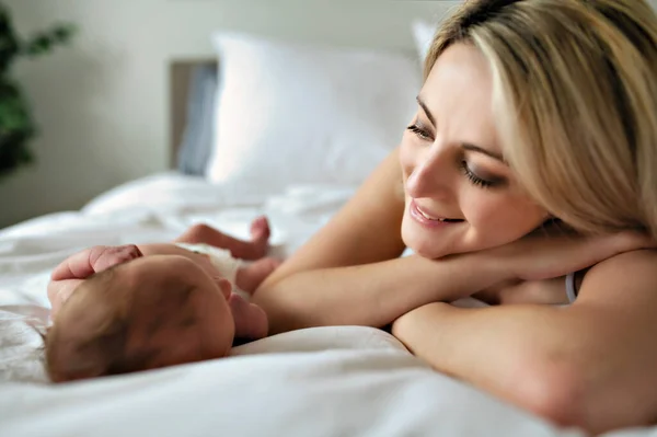 Una mujer con un bebé recién nacido en la cama — Foto de Stock