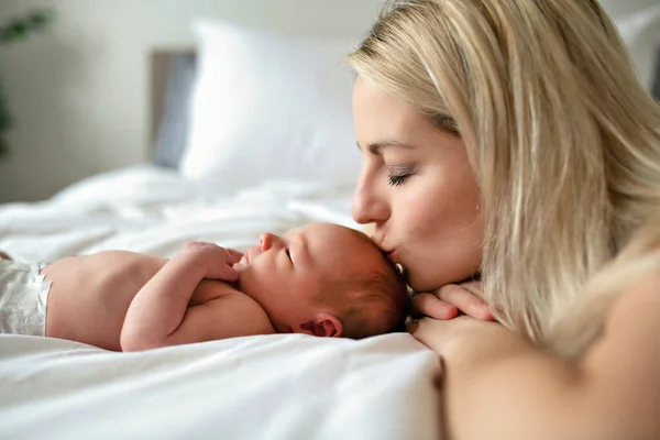 Una mujer con un bebé recién nacido en la cama besarla — Foto de Stock