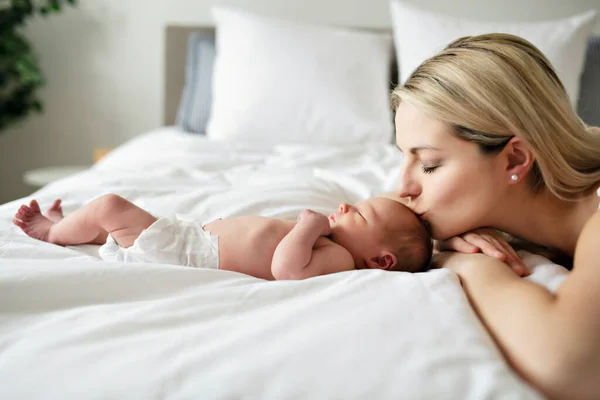 Una mujer con un bebé recién nacido en la cama besarla — Foto de Stock