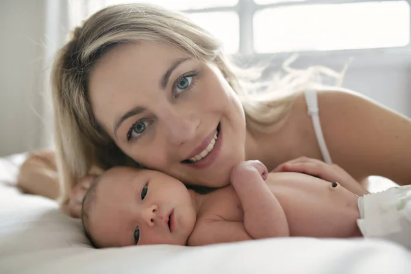A woman with a newborn baby in bed — Stock Photo, Image
