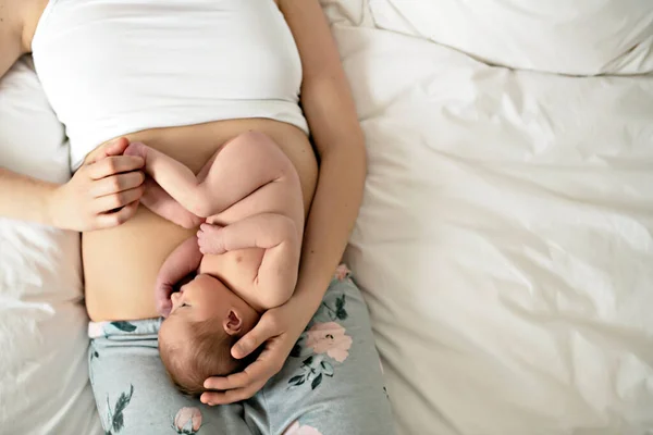 Мать с новорожденным ребенком в постели на животе, как плод — стоковое фото