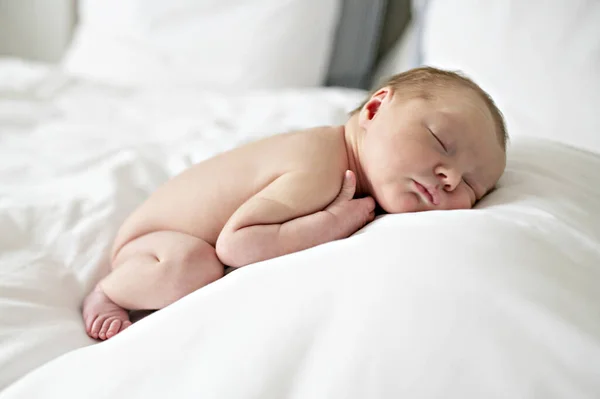 A Sweet newborn baby girl naked sleeping in white bed — Stock Photo, Image