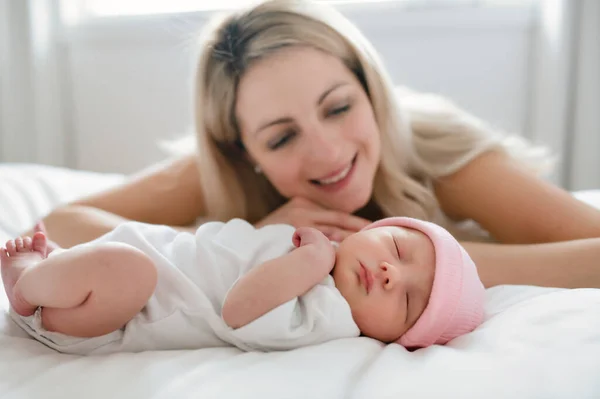 Una mujer con un bebé recién nacido en la cama — Foto de Stock