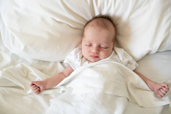 Uma doce menina recém-nascida dormindo na cama branca — Fotografia de Stock