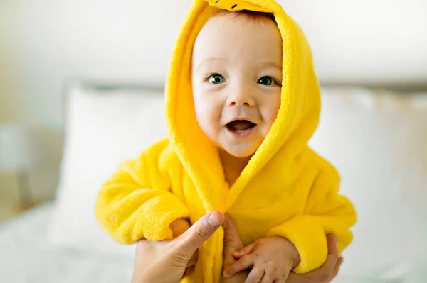 Bebé usando pato de albornoz amarillo en la cama de los padres después del baño — Foto de Stock