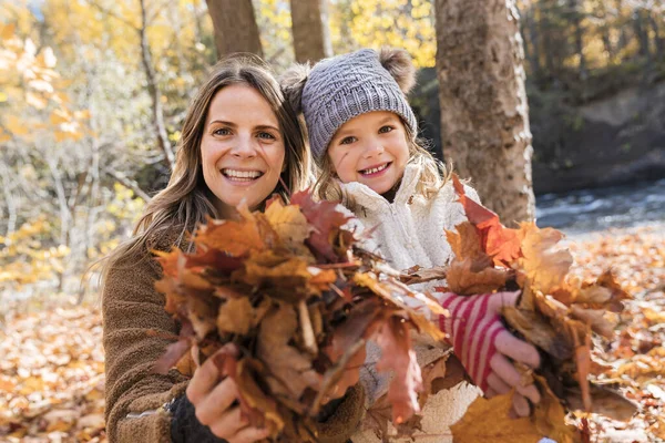 Klein meisje en haar moeder spelen in de herfst park met bladeren, — Stockfoto